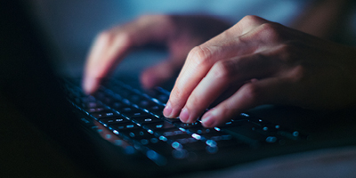 Hand typing on a keyboard, interacting with an AI agent.