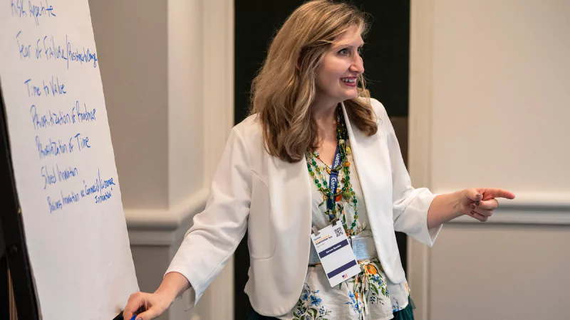 Gartner expert wirting and presenting on a white board with supply chain insights in a workshop session.