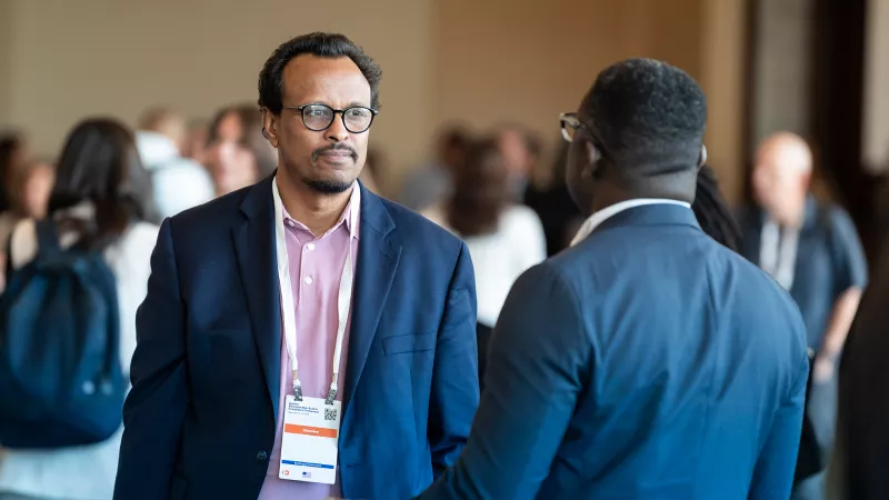 A male conference attendee smiling while listening to a speaker during a session.