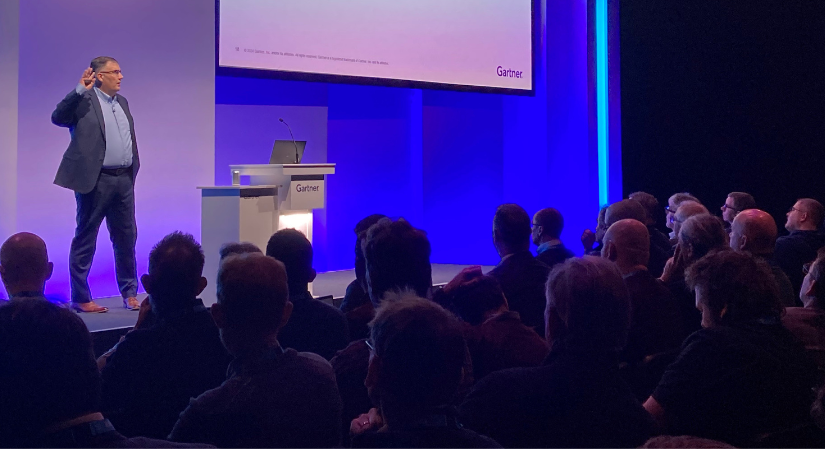 Chris Saunderson on  stage before a crowd at a Gartner event.